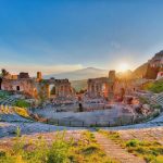 Ancient theatre of Taormina Siciliy Italy with Etna erupting volcano at sunset